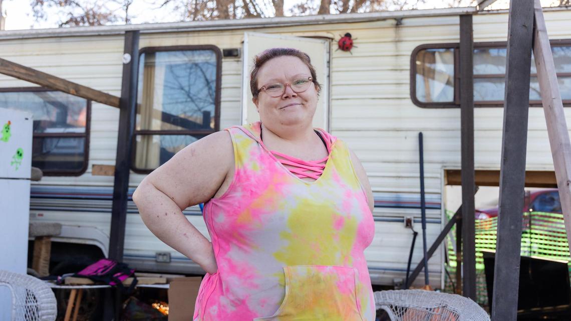 Tiana Hunter stands outside her home at Elm Grove Mobile Home Park as her dog and three cats, out of this view, vie for her attention. Hunter has voiced concerns about the coming Promenade Cottages development, which would force her to leave Elm Grove.