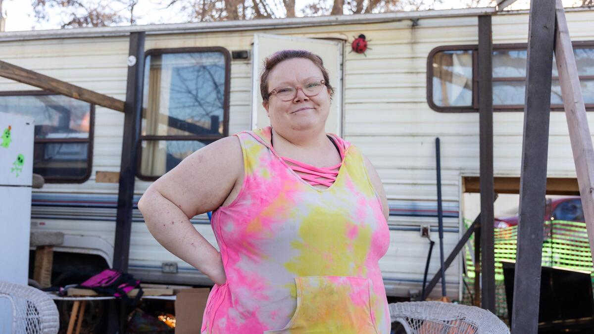 Tiana Hunter stands outside her home at Elm Grove Mobile Home Park as her dog and three cats, out of this view, vie for her attention. Hunter has voiced concerns about the coming Promenade Cottages development, which would force her to leave Elm Grove.