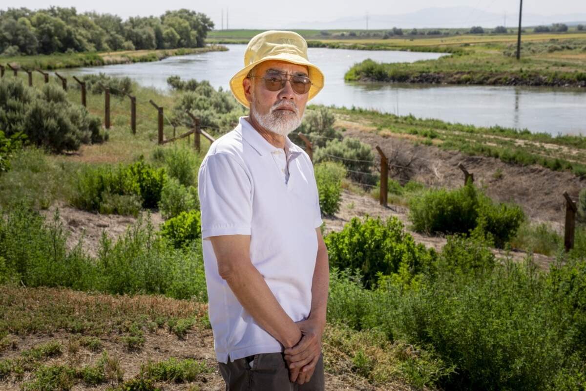 Ken Mochizuki, 69, whose parents were incarcerated at Minidoka, poses in front of reconstructed barbed wire fencing near the camp entrance.