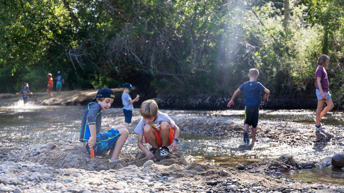 Dane Norsk, 10, left, and Augie Langrill, 7, move sand to create a dam and a side channel stream along the Boise River with other kids from the EverWild Forest School summer camp, Thursday, July, 20, 2023. The cool water and shade along the river banks shielded the children from the sun and heat. The camps run Monday through Thursday every week until mid-August. 