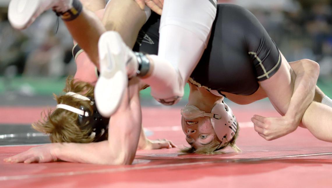 Eagle junior Tanner Frothinger, right, uses his head to find leverage on Kuna sophomore Zanlen Wright in the 5A 126-pound state finals Saturday at Pocatello’s Holt Arena. Frothinger won the bout 8-1 for his third straight state title.
