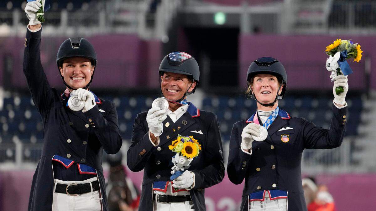 Former Idaho resident Adrienne Lyle, left, celebrates her silver medal Tuesday in the dressage team event alongside teammates Steffen Peters and Sabine Schut-Kery.