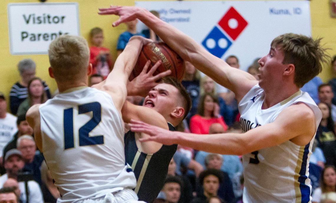 Middleton twin towers Tyler Medaris (12) and Tyler Robinett reject a drive by Kuna’s Lance Ray, forcing a turnover in the first half of the 4A District Three championship Thursday, Feb. 27, 2020 at Kuna High School. MIddleton won the district title with a 65-54 victory.