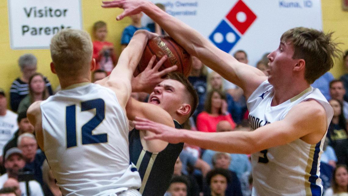 Middleton twin towers Tyler Medaris (12) and Tyler Robinett reject a drive by Kuna’s Lance Ray, forcing a turnover in the first half of the 4A District Three championship game Thursday at Kuna High.