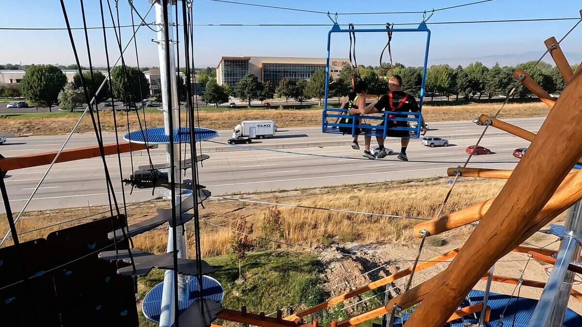 Kayla Romano and Gavin Gard sit on a ski-lift chair watching cars go by on the freeway.