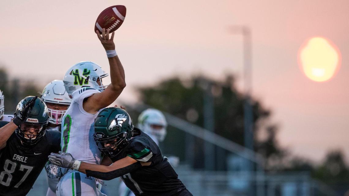 Eagle’s pass rush hurries Mountain View quarterback Jake Farris into an incomplete pass Friday at Thunder Stadium in Eagle. An amber glow was cast on the field as the sun lowered into a smoky horizon.