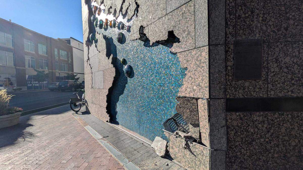 Cars drive by on Front Street by the Grove Hotel, where damage right by the River Sculpture is visible on Wednesday afternoon.