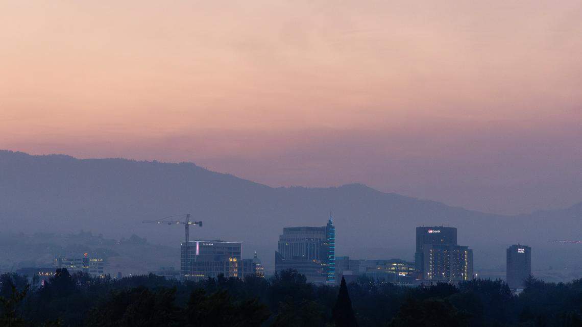 Smoky skies from regional wildfires obscure the view of the foothills at dawn over downtown Boise, July 23, 2024.