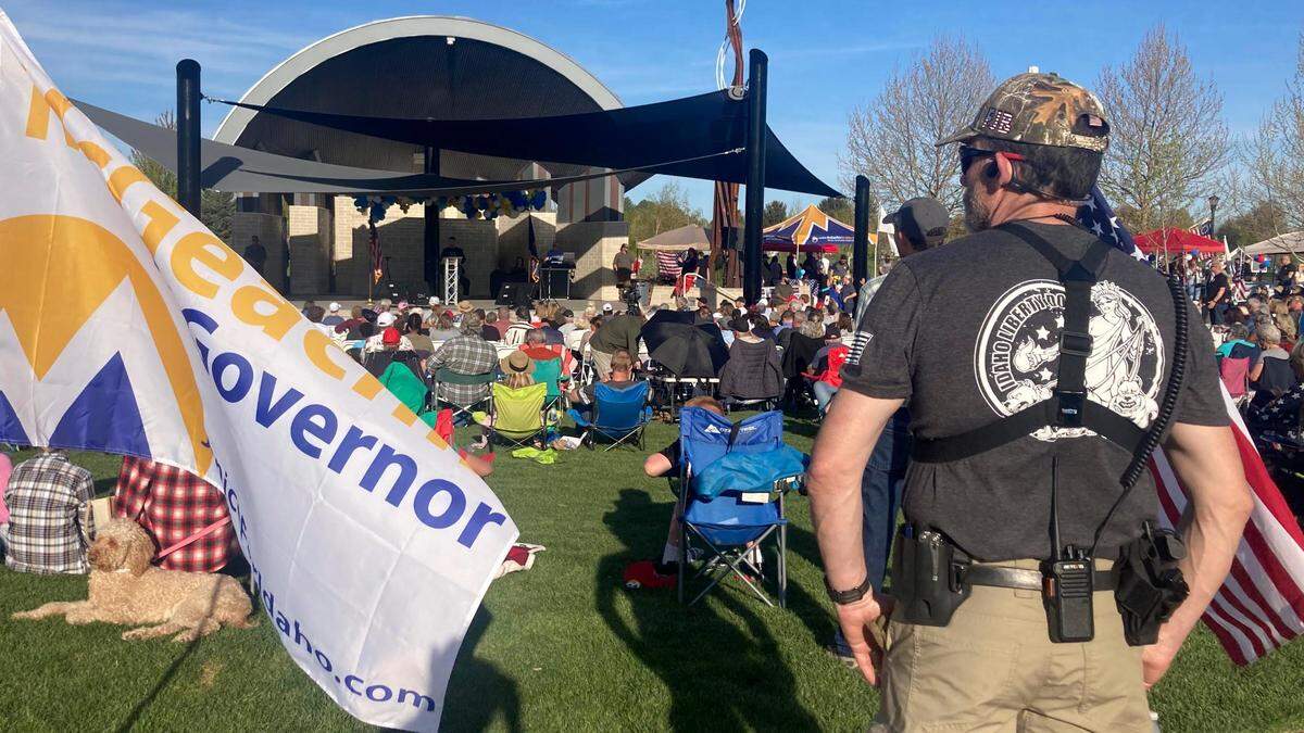 A member of the Idaho Liberty Dogs, a right-wing citizen group, stands guard with a holstered handgun, walkie-talkie and earpiece at a campaign rally for Lt. Gov. Janice McGeachin in her bid for governor, held May 4 at Julius M. Kleiner Memorial Park in Meridian.
