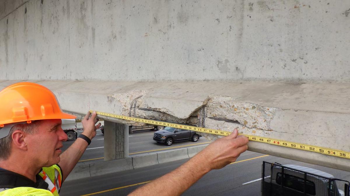 A worker measures the damage to the Robinson Road overpass above Interstate 84 eastbound in Nampa. A large excavator crashed into the bridge on Wednesday.