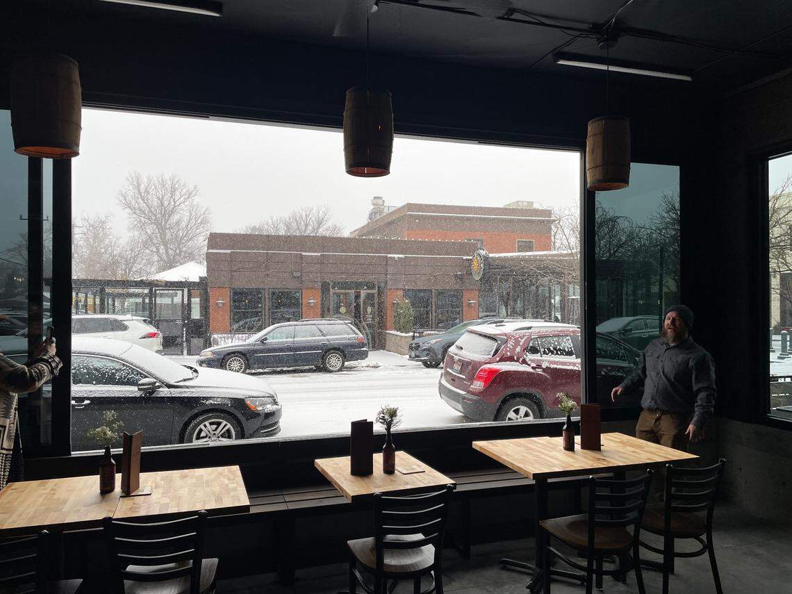 Lost Grove owner Jake Black, right, stands next to one of the large windows that open to a view of Eastman Street.