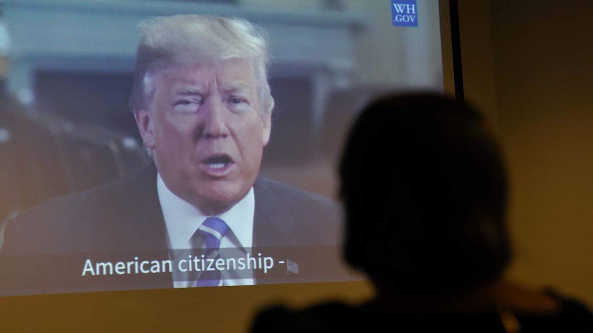 Maria Valles Bonilla, right, from El Salvador, watches a taped video message from President Donald Trump after taking the Oath of Allegiance during a naturalization ceremony at U.S. Citizenship and Immigration Services office Tuesday, Nov. 6, 2018, in Fairfax, Va.