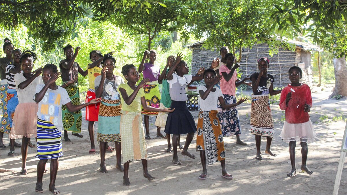 Members of the Nhanbita girls club dance and sing to welcome guests to their school in June in Mozambique.