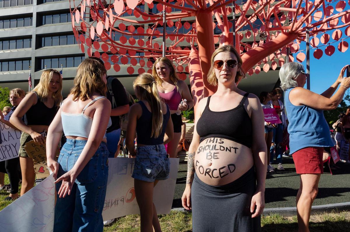 Megan Ewins shows off a message on her exposed, pregnant belly that reads, “This shouldn’t be forced.” Ewins was one of many who attended a protest against banning abortion Saturday at Cherie Buckner Webb Park in Boise.