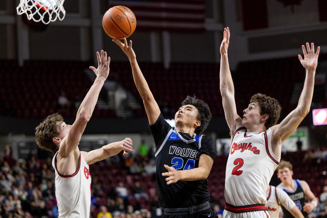 Timberline guard Alex Ko drives to the hoop defended by Owyhee’s Jackson Rasmussen, left, and Jackson Rogers in the 5A District Three boys basketball championship game Friday at Idaho Central Arena in Boise.