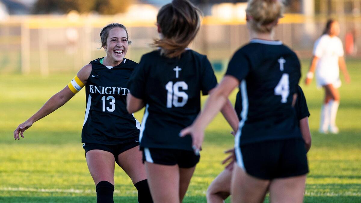 Bishop Kelly midfielder Gracie Rhodes celebrates with teammates after the Knights won their 14th straight 4A District Three girls soccer tournament title last fall. The Knights are asking the IHSAA to move up a division in boys and girls soccer and boys and girls swimming.