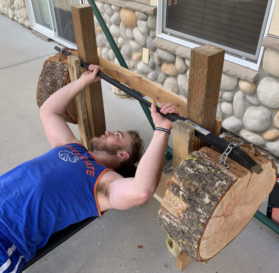 Boise State long snapper Daniel Cantrel gets a workout in with homemade weights fashioned out of a crowbar and pieces of tree trunk.