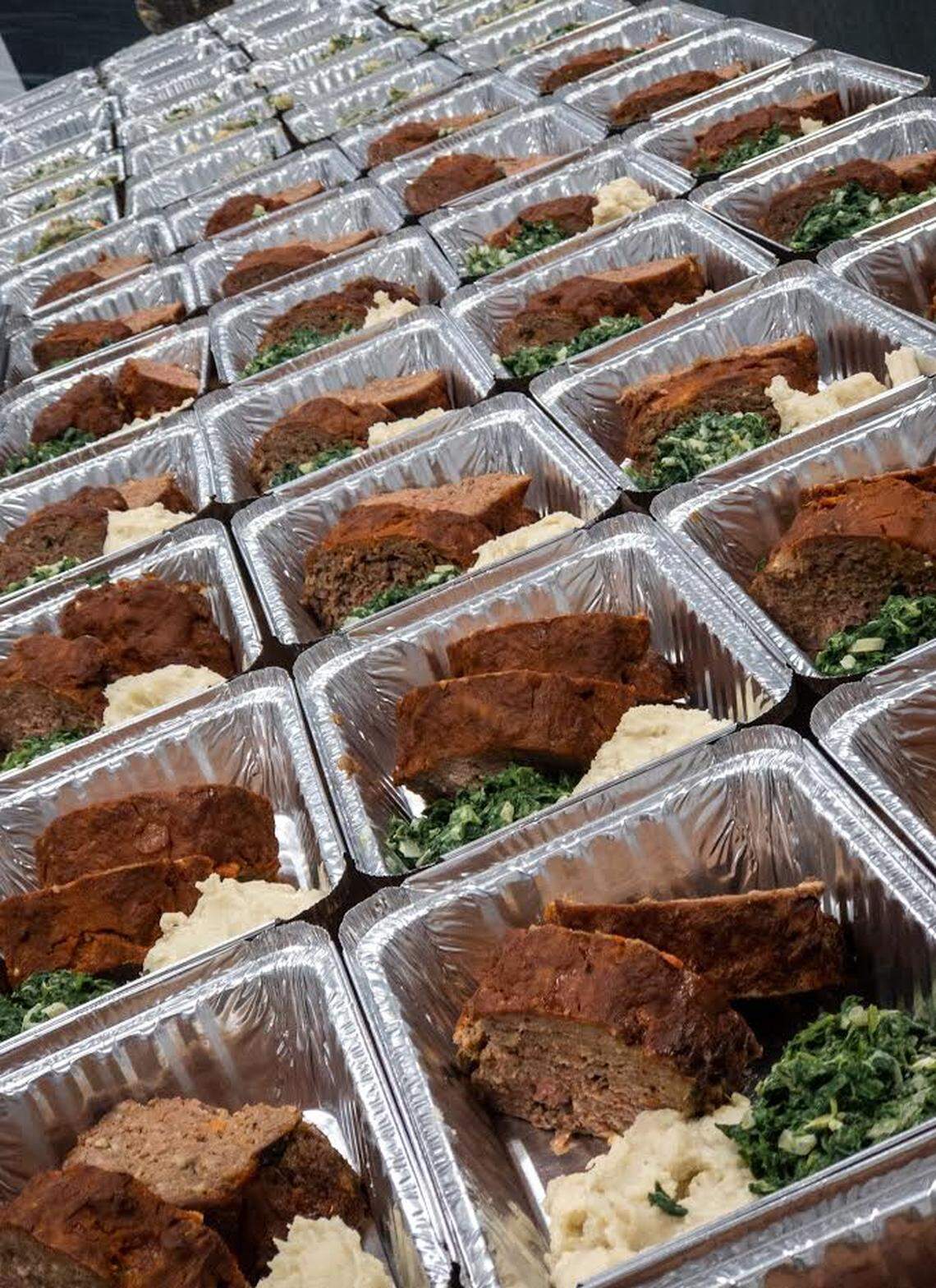 Meals of meatloaf, mashed potatoes and spinach getting assembled in the prep line at Kin.