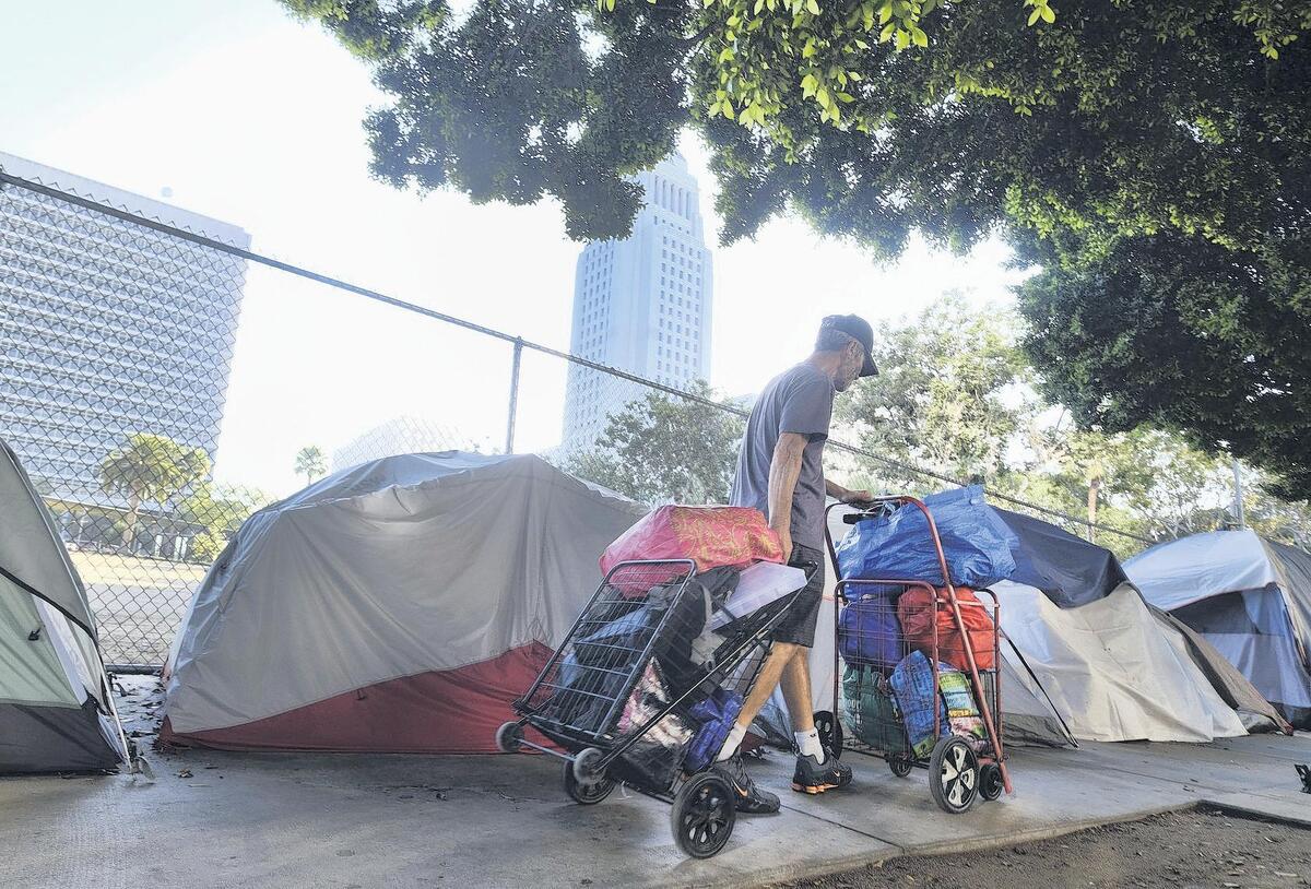 A homeless man moves his belongings from a street behind Los Angeles City Hall as crews prepared to clean the area. L.A. has a massive homeless population that is only growing.