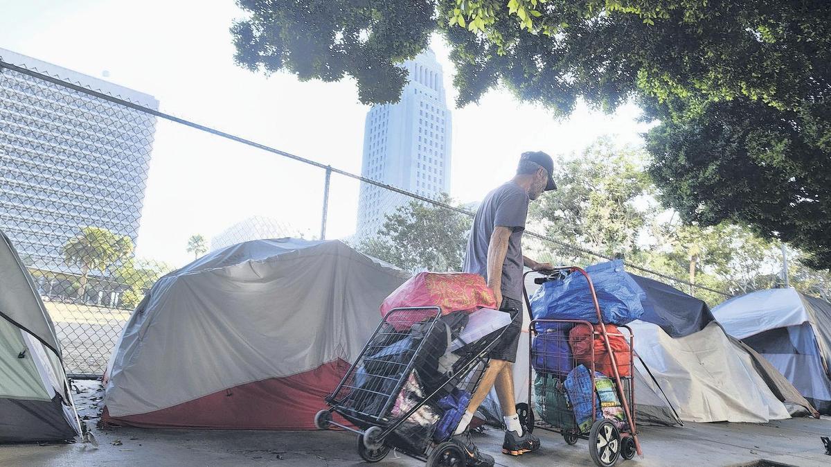 A homeless man moves his belongings from a street behind Los Angeles City Hall in this file photo.