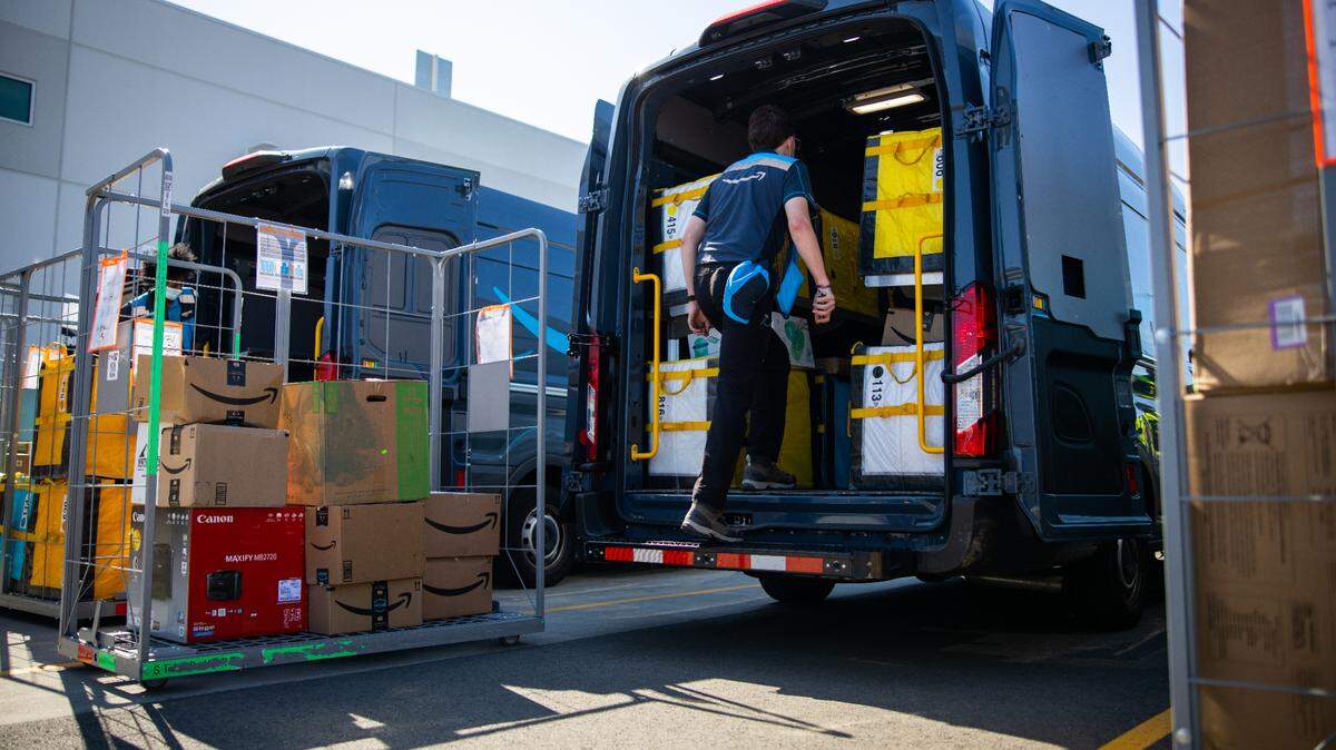 An Amazon driver loads packages into a van from a delivery station to deliver them to customers’ homes.