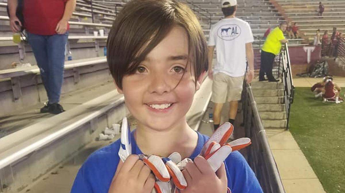 Liam Land of Columbus, Georgia, shows off the gloves Boise State nose guard Sonatane Lui gave him after the Broncos’ 56-20 win over Troy on Sept. 1 in Troy, Alabama.