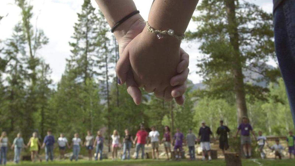 Camp Rainbow Gold campers and counselors join hands and form a circle before dinner.