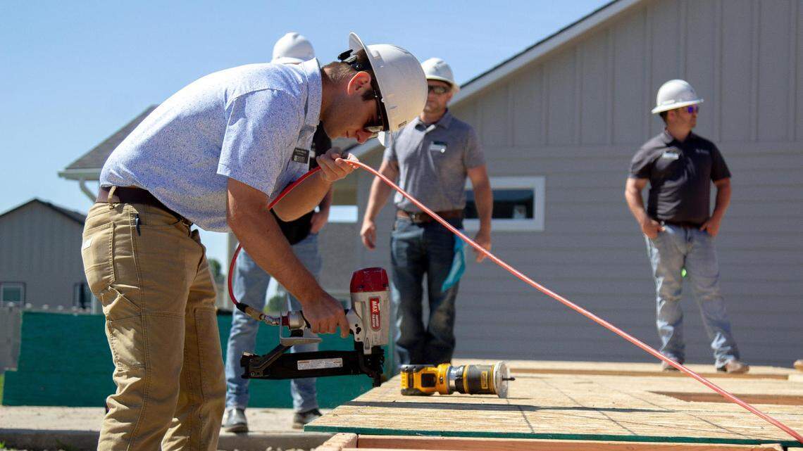 Darren Henry, of Hayden Homes, uses a nail gun to secure the plywood to the frame of a house in 2023.