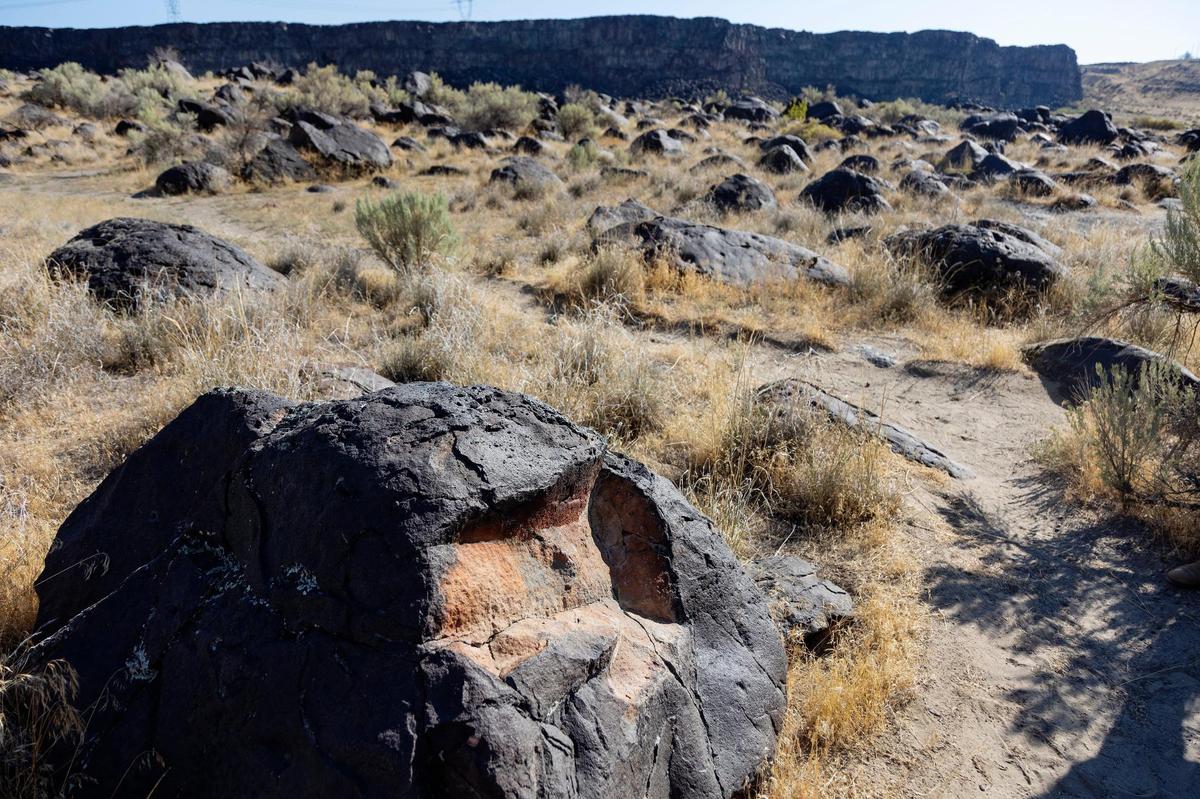 The rock at the bottom left of the image shows the patination— the change of color from the rust colored inside to the dark outside.