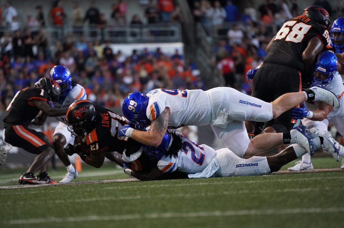 Boise State defensive tackle Scott Matlock and nickel Tyreque Jones bring down Oregon State running back Trey Lowe during the Broncos’ 34-17 loss in Corvallis, Oregon, on Saturday.