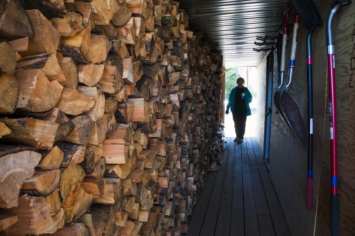 Leslie Tengelsen walks through the firewood storage shed below the new Hennessy Yurt.