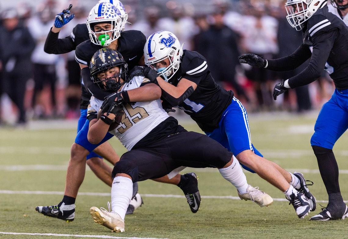 Kuna running back Geno Salas drags a pair of Timberline defenders for a first down in the first round of the 6A state playoffs last fall. 