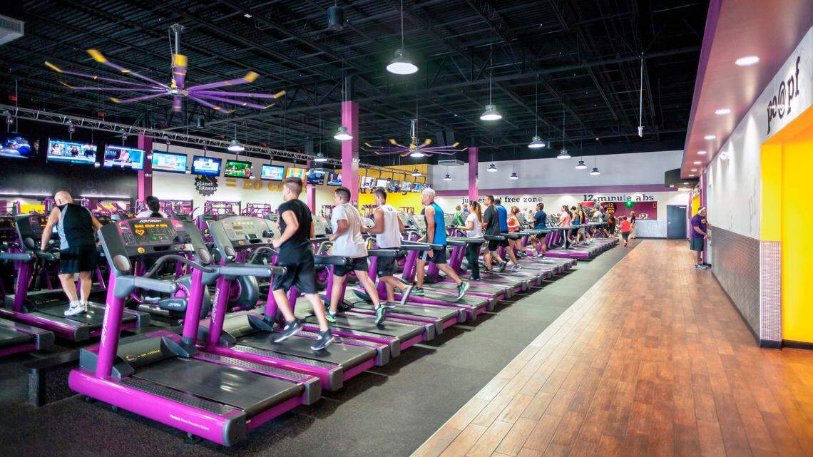 The interior of a typical Planet Fitness has rows of cardio machines and TV sets.
