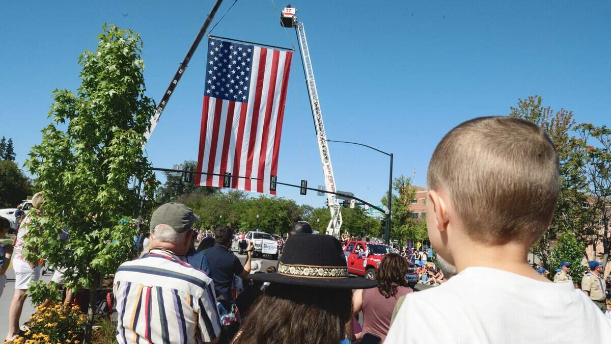 A large American flag stretches across the intersection of Capitol Boulevard and River Street, as parade attendees line the sidewalks below to watch Boise's Fourth of July parade make its way through downtown on Saturday.