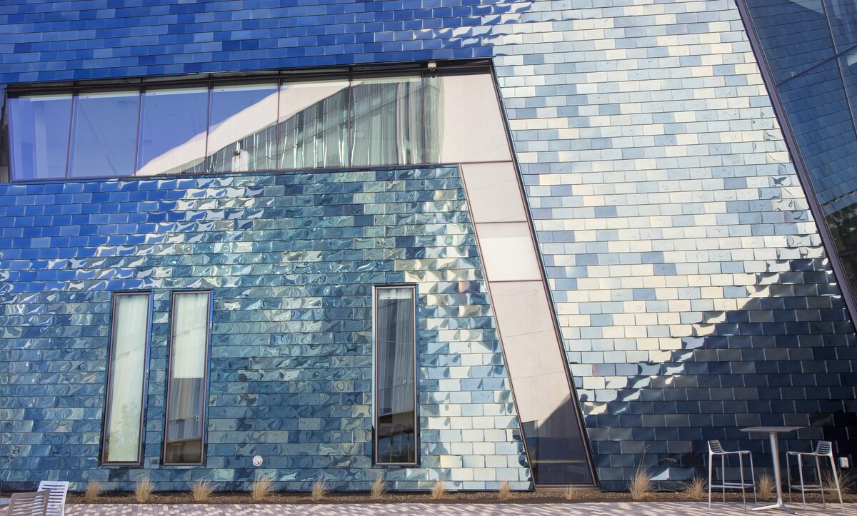 The blue stainless steel tiles reflect colors from black to gold, depending on the sun.