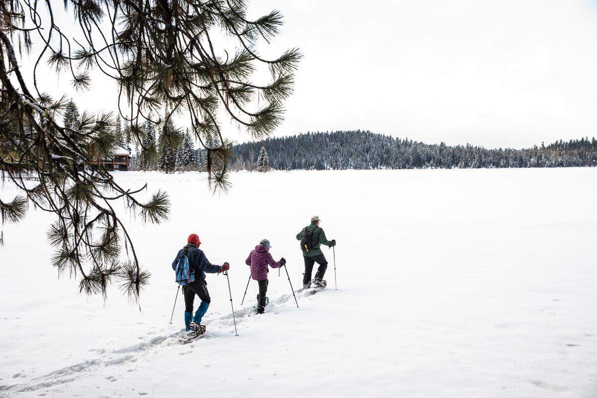 Jeff Canefield, and Edie and Thomas Welty snowshoe on Payette Lake in McCall, Idaho.