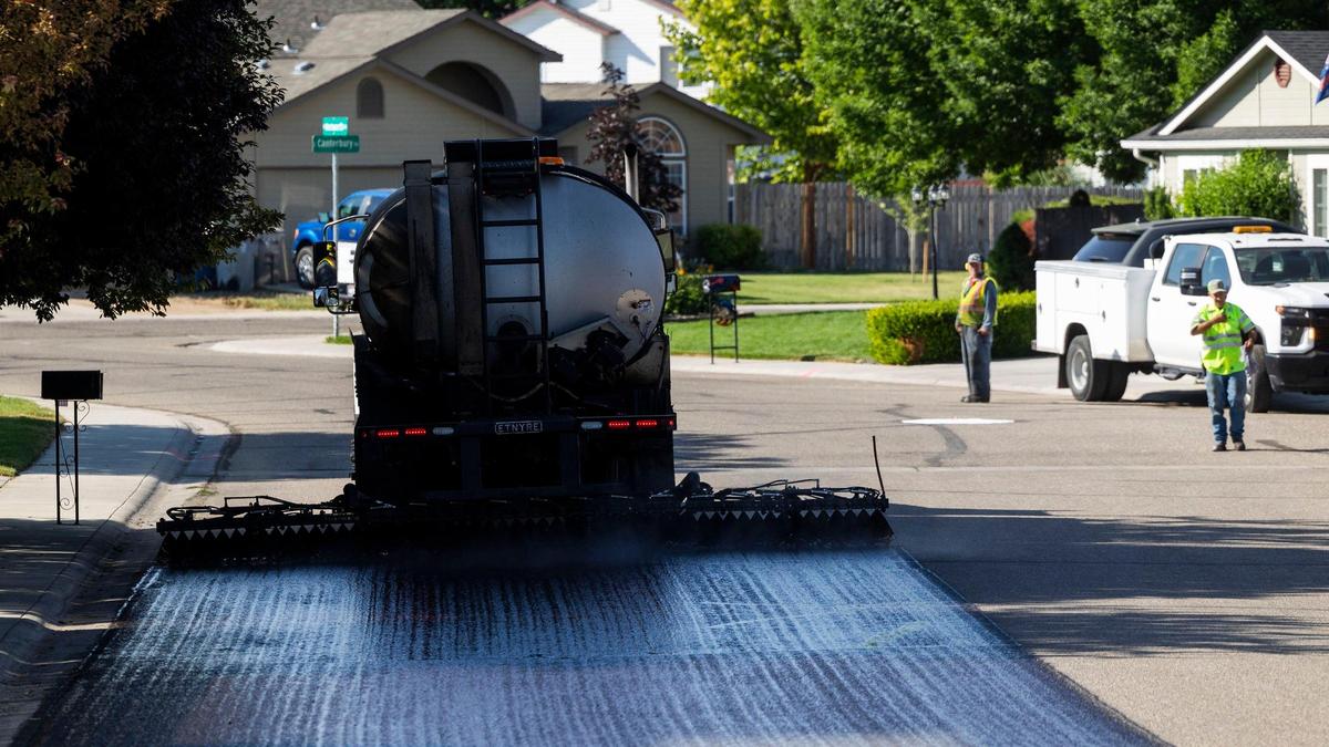 A fresh coat of oil precedes a chipper that quickly drops a layer of chipped rock to resurface a residential street. The chipper must pour the layer of chips onto the road before the oil hardens, which takes only one minute.