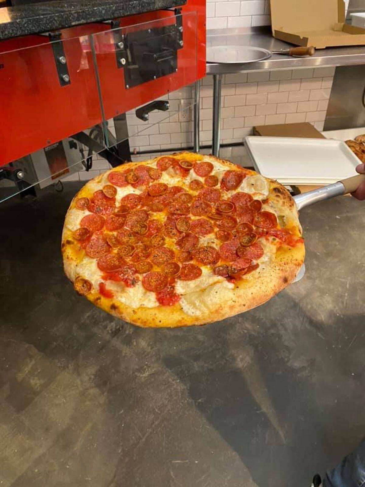 A pepperoni pizza is pulled from the 3 Wood oven.