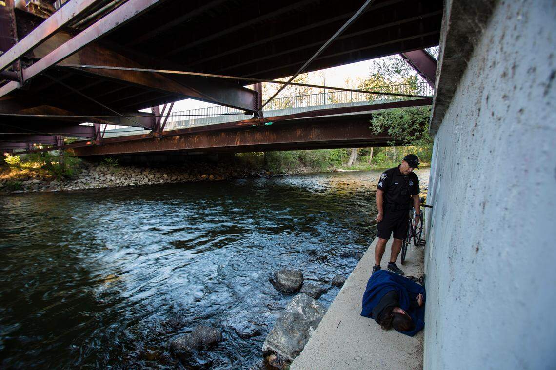 Sgt. Craig Nixon of the Boise Police Department’s Micro District Bike Patrol talks with a homeless man by the Boise River on a footing of the Eighth Street pedestrian bridge.
