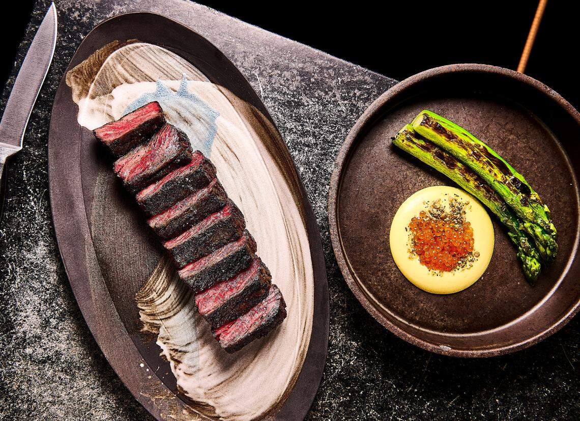 Niku Steakhouse serves ember roasted meats and vegetables, such as the plated wagyu steak and grilled asparagus shown here.