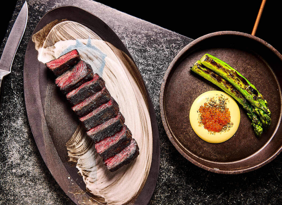 Niku Steakhouse serves ember roasted meats and vegetables, such as the plated wagyu steak and grilled asparagus shown here.