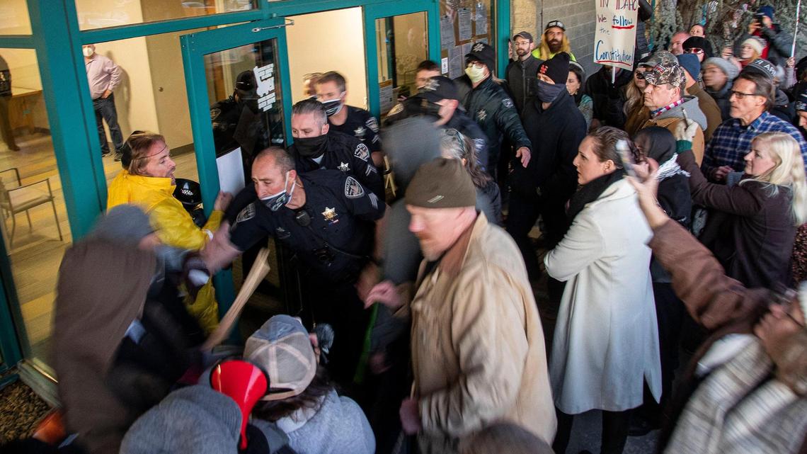 Protesters try to force through the doors at the Central District Health offices during a special meeting of the board Dec. 4, 2020, in Boise. Police forcibly prevented people from pushing through.