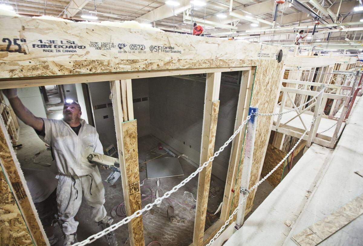Troy Langford stands on stilts while drywall mudding the interior of a modular apartment unit in an assembly line at Guerdon Modular Buildings in 2012 in East Boise.