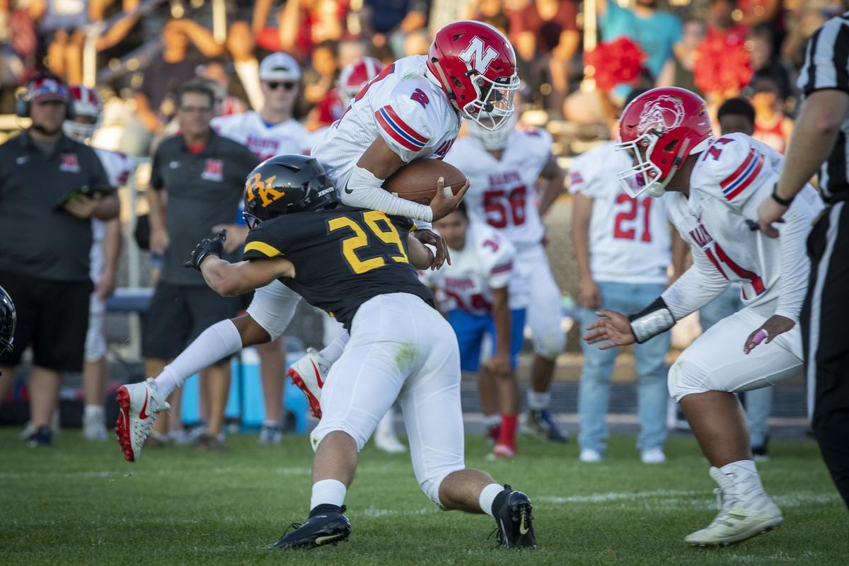 Nampa quarterback Donavon Estrada tries to leap over Bishop Kelly’s Jay Horning in the season opener for both teams.