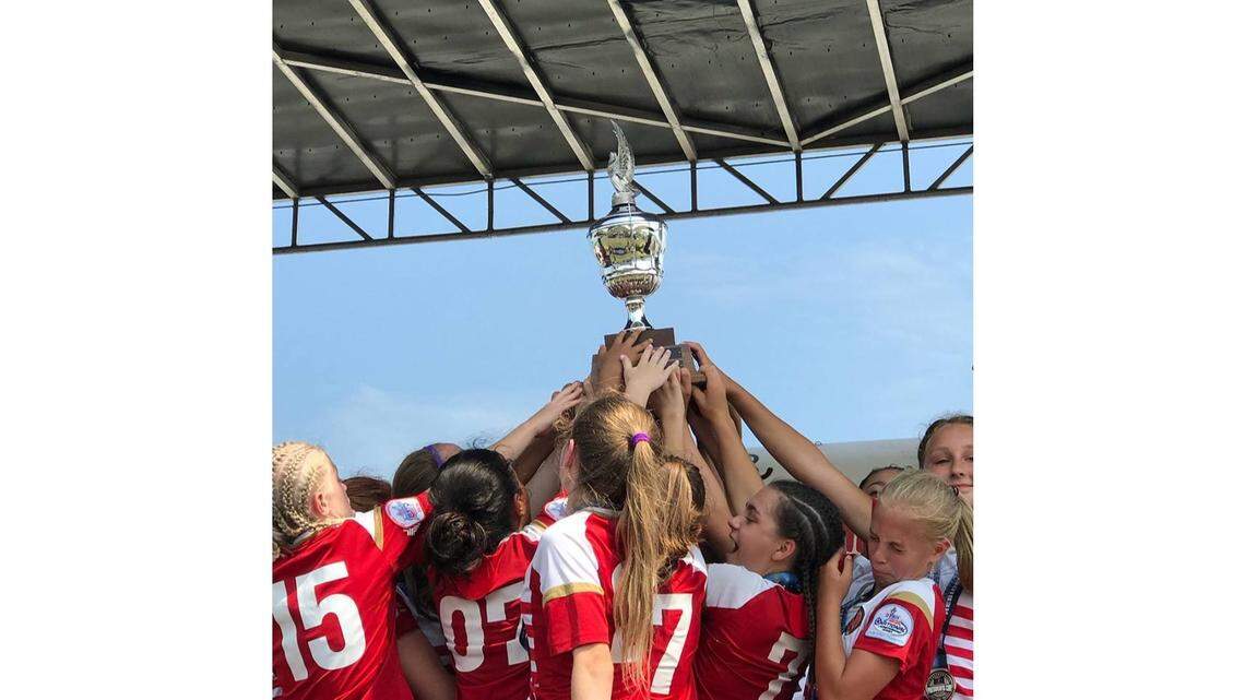 FC Nova’s U-13 girls soccer team lifts the championship trophy after winning the U.S. Youth Soccer Presidents Cup on Sunday in Indiana.