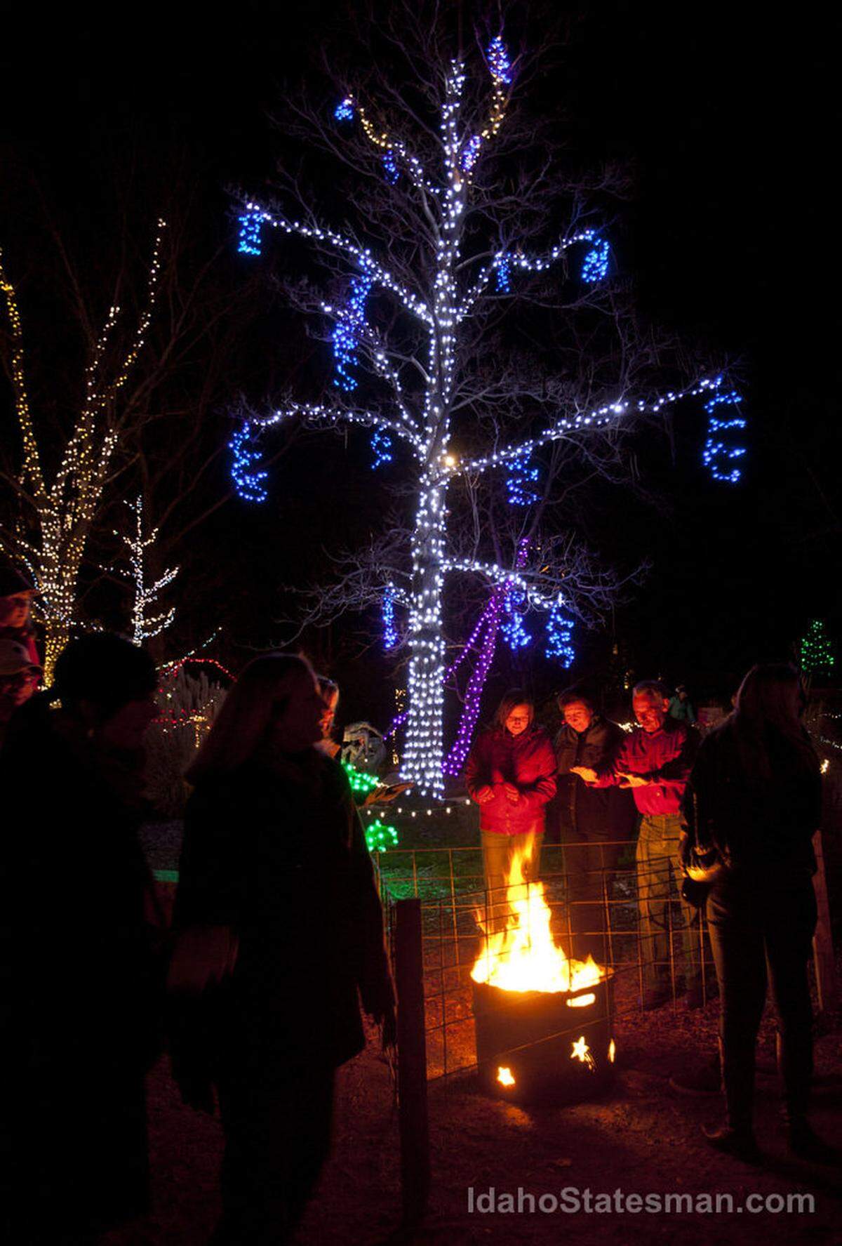 Sylvia Murdock, left, and her mother, Dianna Garcia, and Kelly Chaffin, warm up by the fire. “This is a great way to get in the Christmas spirit,” says Sylvia. More than 270,000 lights have transformed the Idaho Botanical Garden into the dazzling annual Winter Garden aGlow.