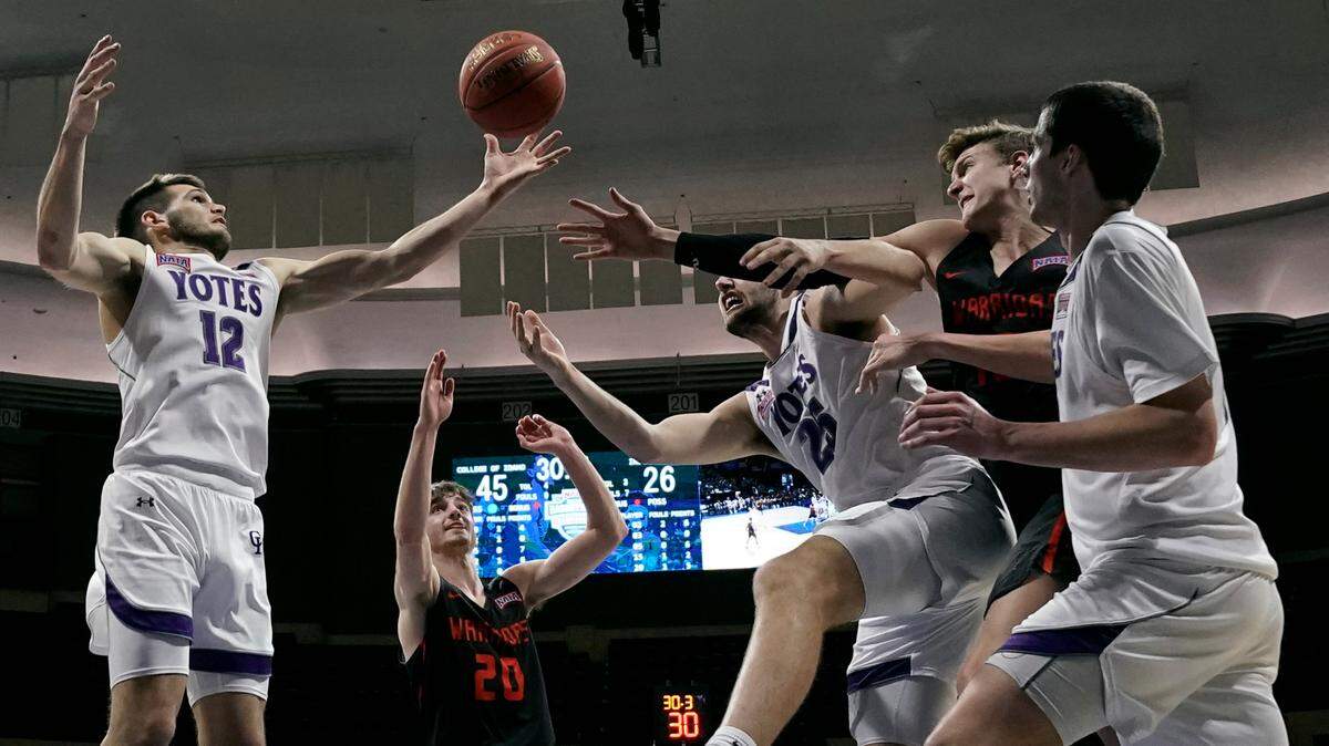 College of Idaho guard Jake O’Neil (12) grabs a rebound during the first half of the NAIA men’s national championship college basketball game against Indiana Tech Saturday in Kansas City, Missouri.