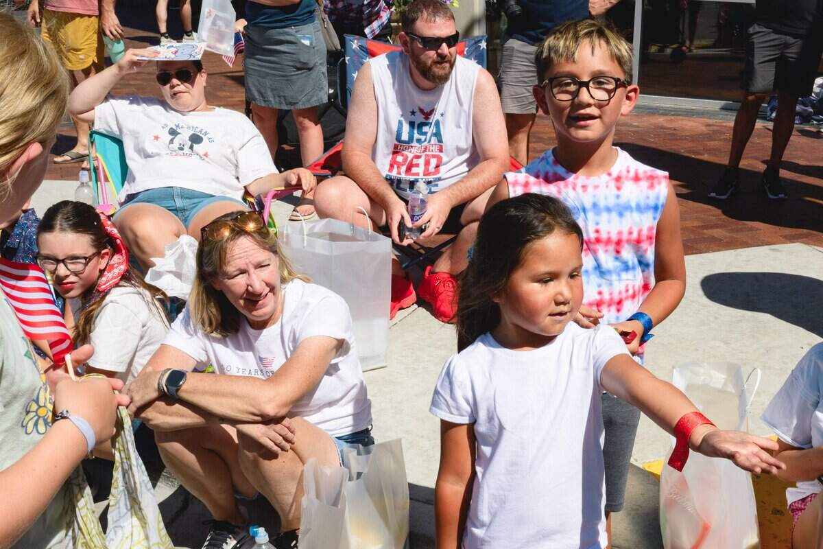 Children and families line the street as candy and goodies rain down from passing floats during Boise's Fourth of July parade Saturday.