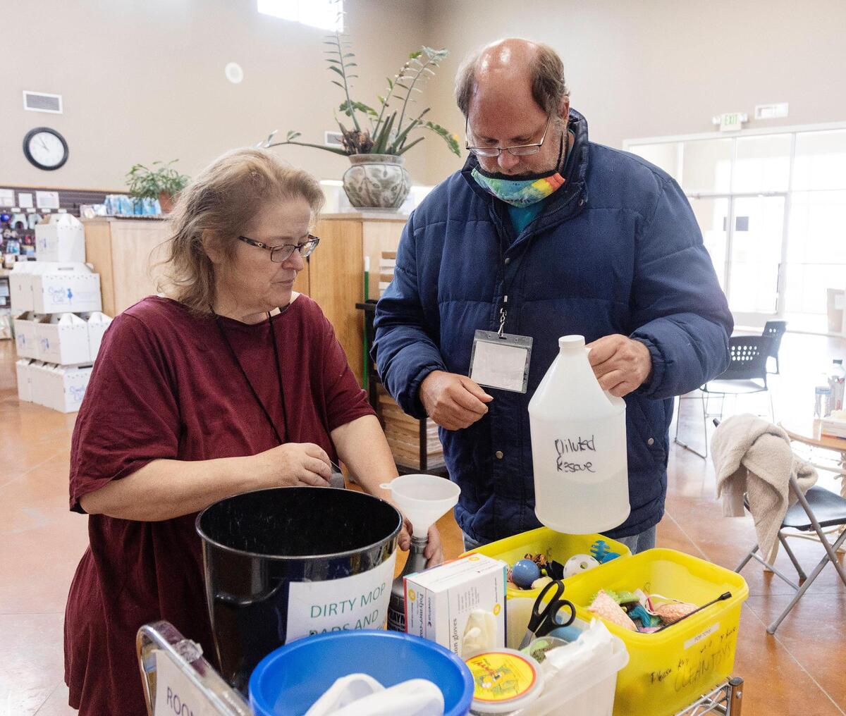 Wendy Eckert, owner of Unity Services and Meridian Developmental Services, instructs client Brian Prosynchak on refilling cleaning supplies at Simply Cats as part of their weekly volunteer and social outing for developmentally disabled adults.