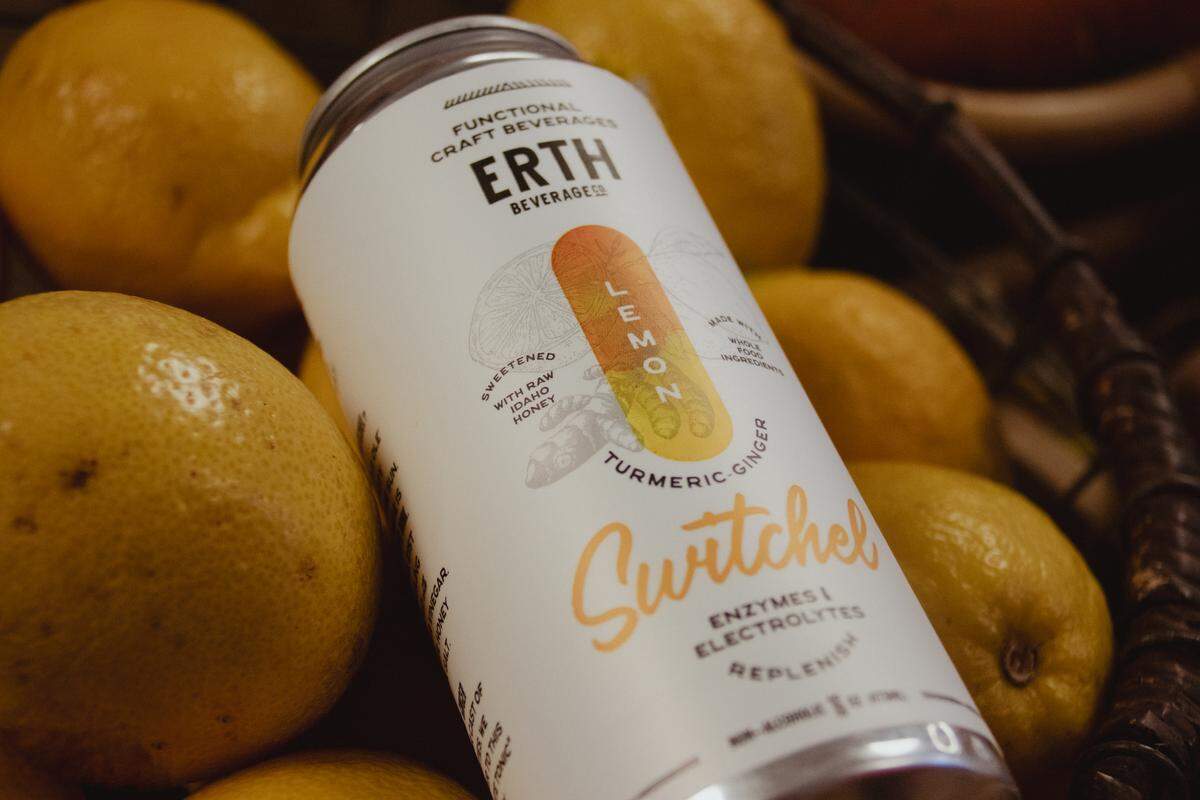 A can labeled: ERTH Beverage Co., lemon turmeric-ginger switchel. It is placed in a basket of lemons.